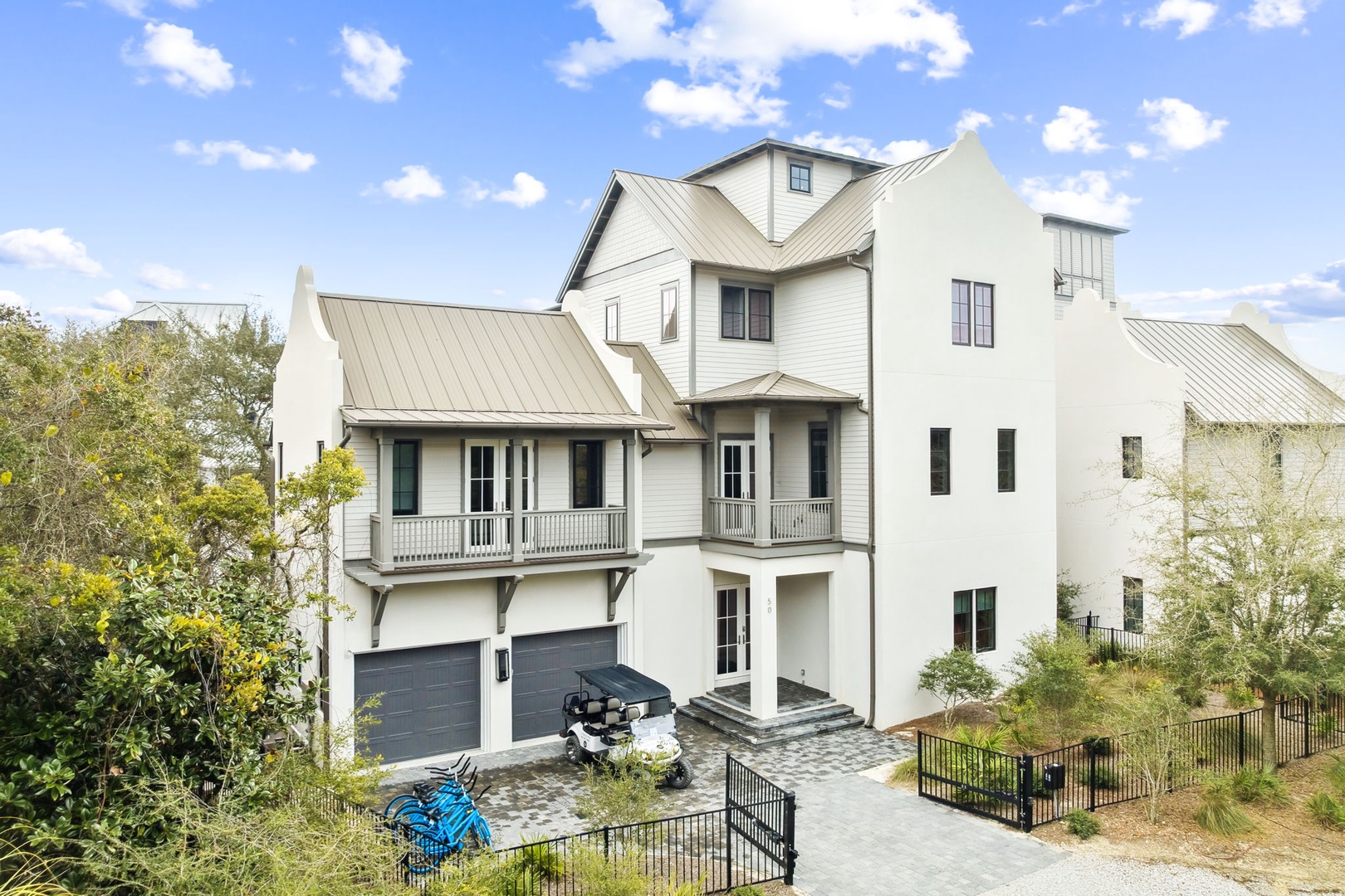 Modern coastal home featuring spacious balconies and convenient parking for beach gear and golf carts in the driveway.