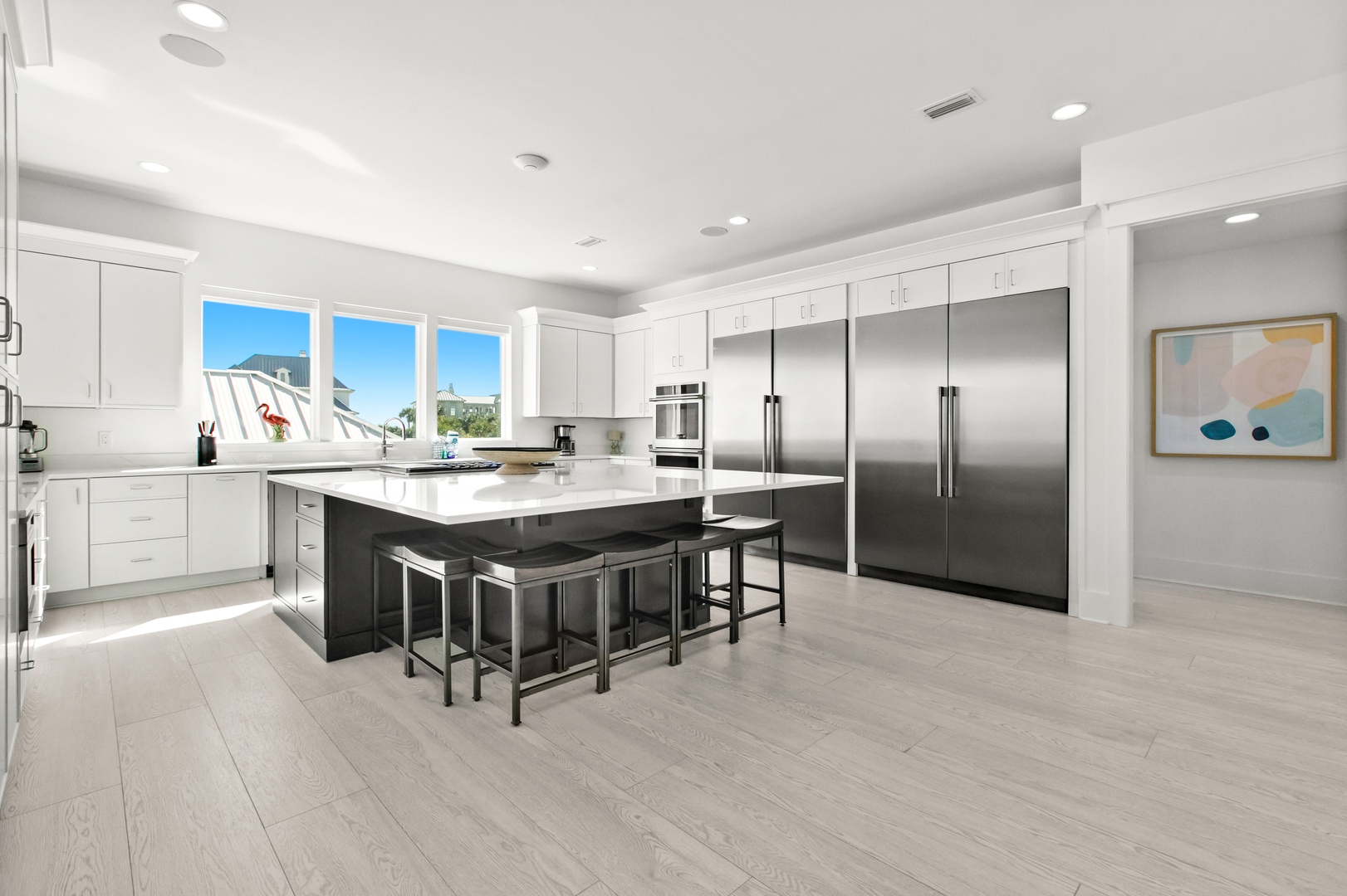 Your modern kitchen features crisp white cabinetry, a spacious island with seating, and stainless steel appliances—perfect for preparing meals together and lingering over morning coffee.
