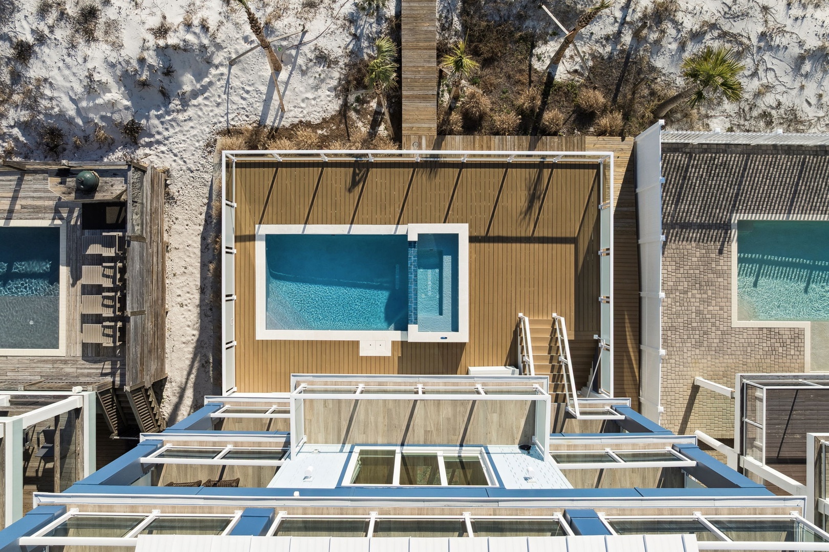 Aerial view of a beachfront property featuring modern architecture with private pools and direct beach access.