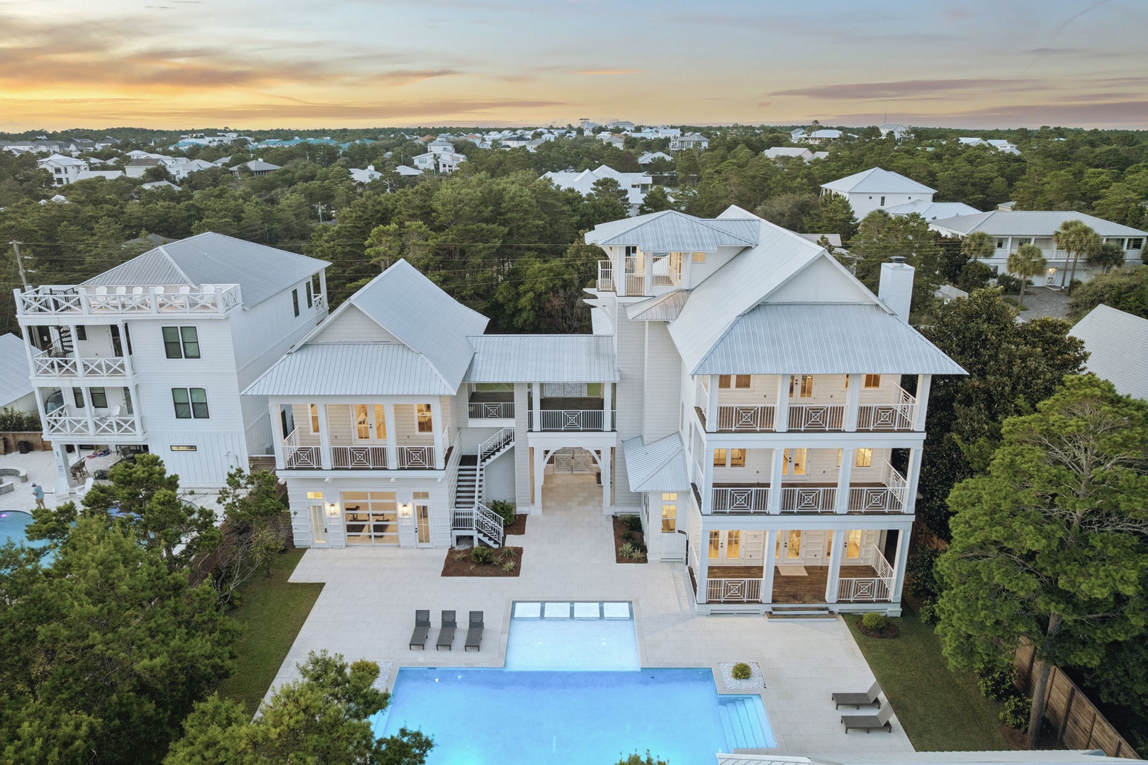 An elegant coastal property with a sparkling pool and spacious balconies, set among lush greenery in a peaceful neighborhood near the beach.