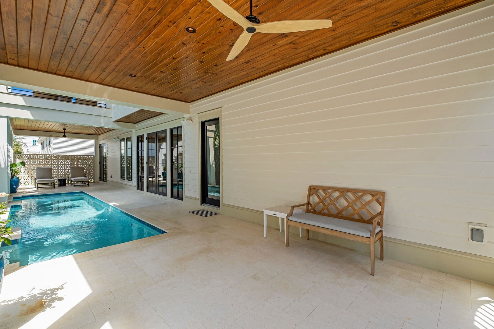 Unwind in your private covered terrace with pool views, featuring elegant furnishings and a ceiling fan for comfort.