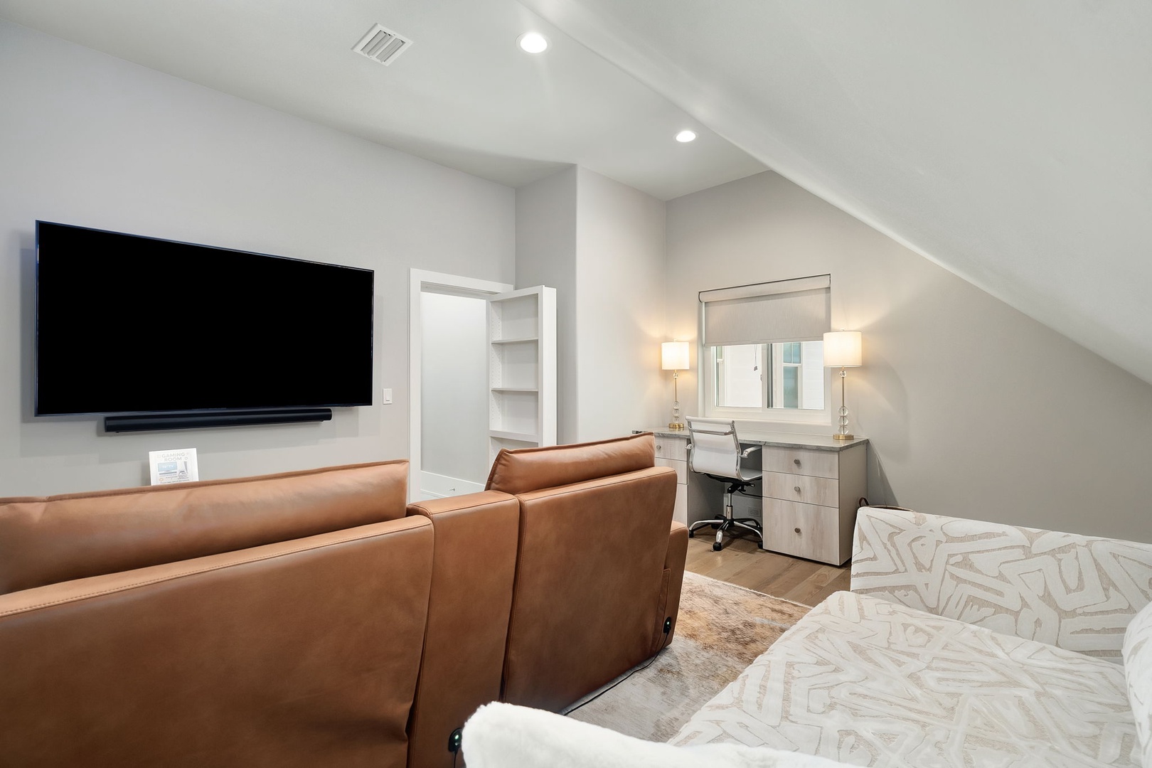 Unwind in your stylish bedroom with plush leather seating facing the wall-mounted TV, perfect for cozy movie nights in comfort.