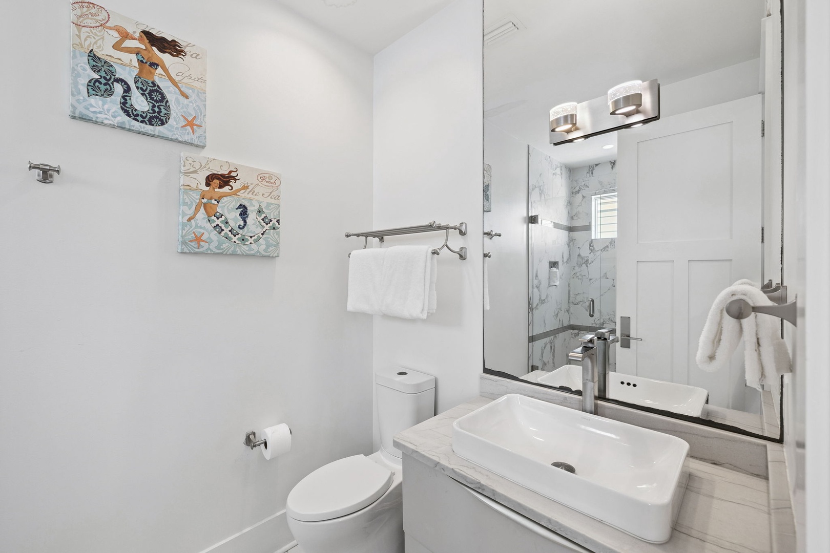 Refresh in your stylish bathroom featuring modern fixtures, soft towels, and charming coastal artwork to brighten your morning routine.