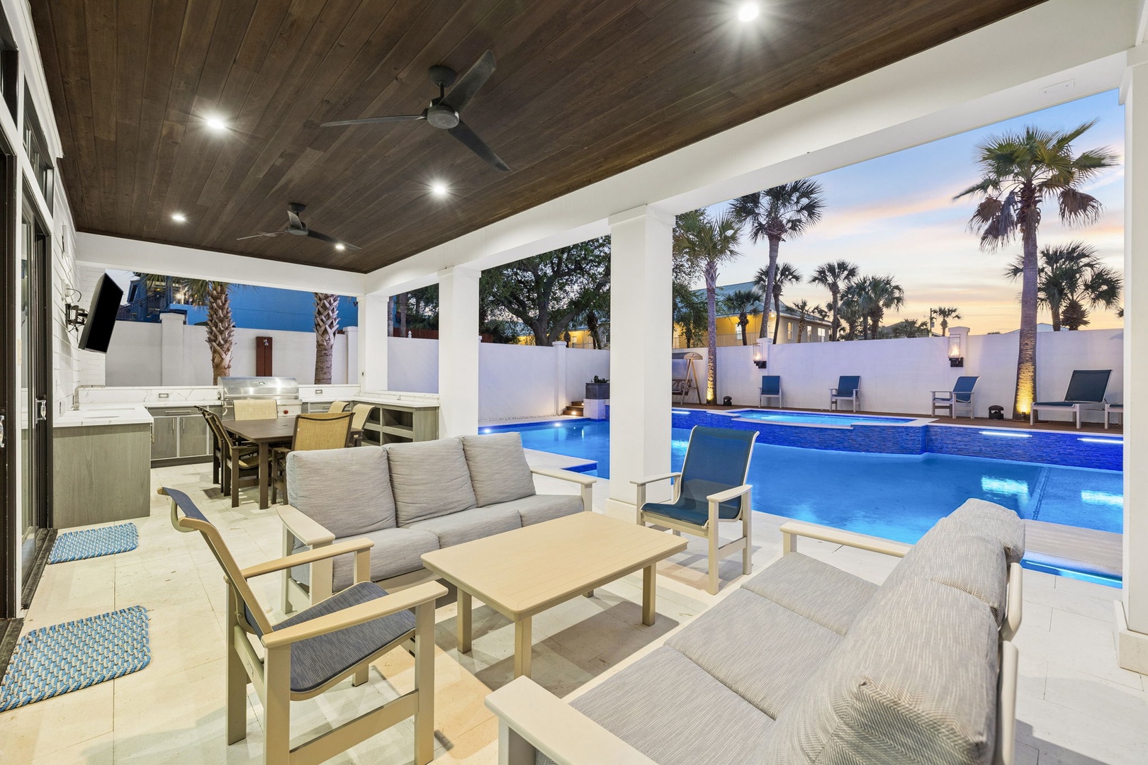 Unwind in your elegant covered patio with plush seating overlooking the sparkling pool, perfect for evening relaxation under warm tropical skies.