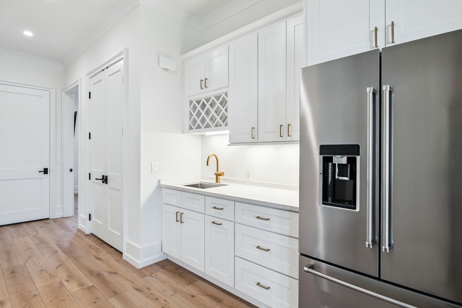 Step into your bright, modern kitchen with pristine white cabinetry, elegant gold fixtures, and premium stainless steel appliances ready for your culinary adventures.