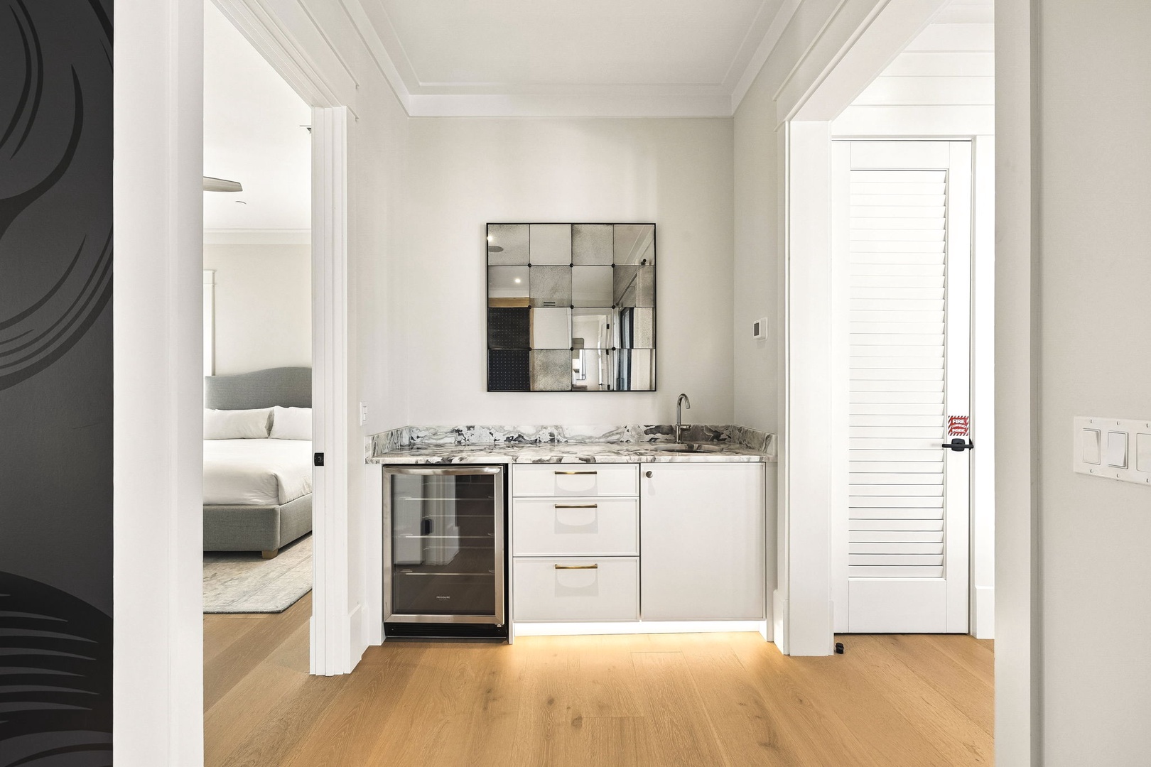 A sleek kitchenette with marble countertops, modern cabinetry, and a built-in beverage cooler creates your perfect space for refreshments. Warm wood floors and elegant crown molding add a sophisticated touch to your retreat.