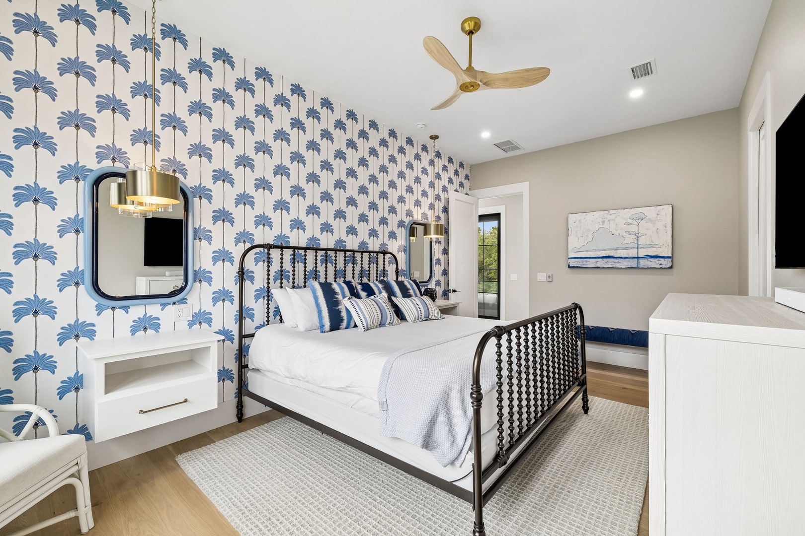 Unwind in your coastal-inspired bedroom with tropical palm wallpaper, crisp linens, and a breezy ceiling fan—your perfect retreat for restful nights.