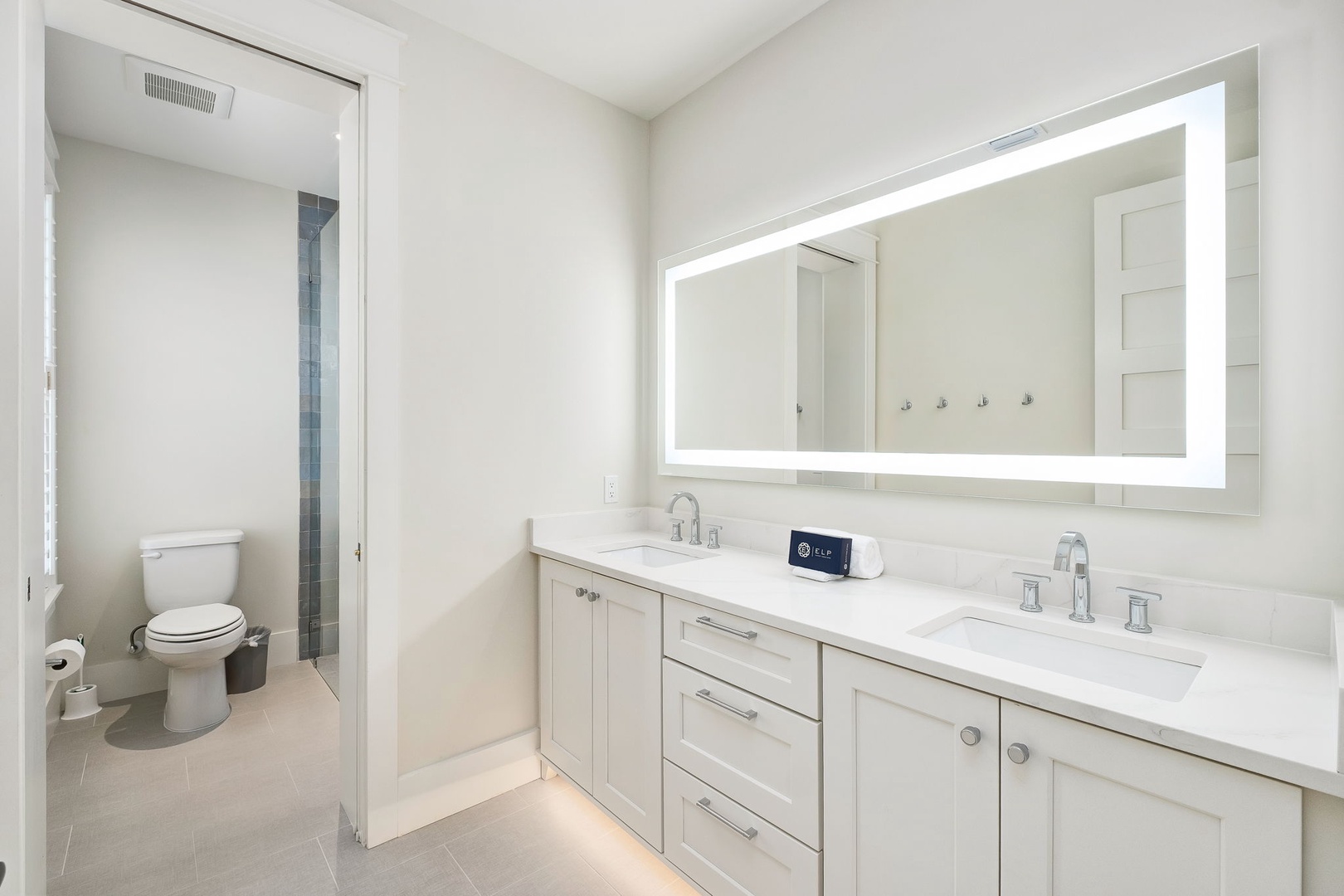 Your bright, modern bathroom welcomes you with dual vanities, ambient mirror lighting, and sleek tile floors—perfect for relaxing morning routines before exploring the area.
