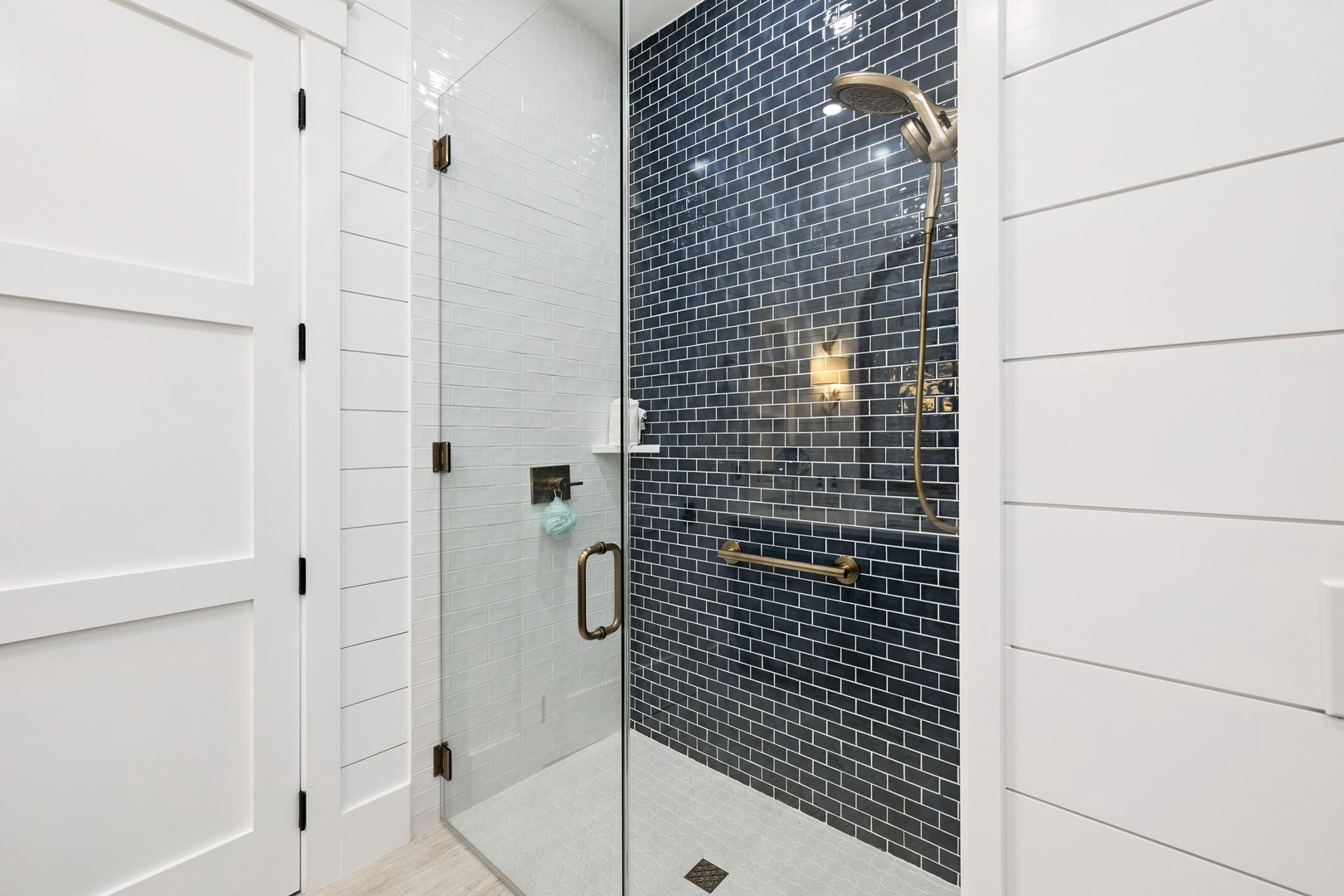 Step into your luxurious glass-enclosed shower featuring stunning navy subway tile and gleaming brass fixtures for a spa-like experience.