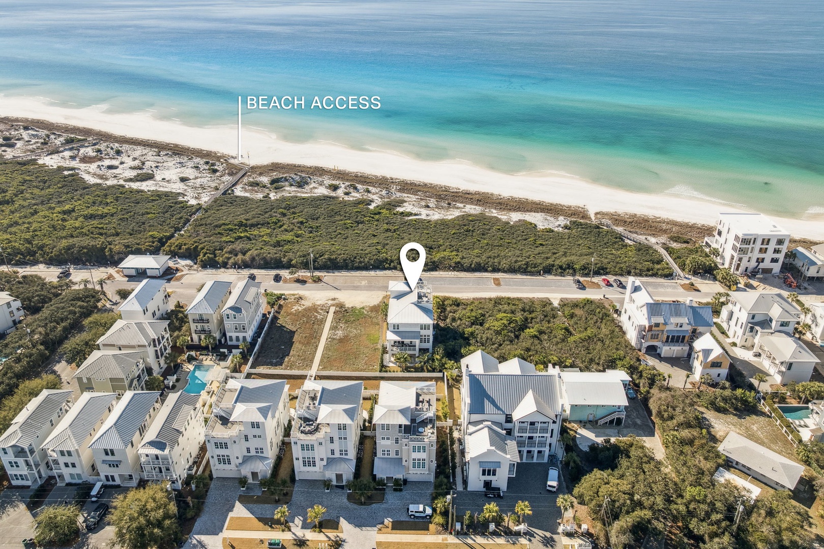 Aerial view of coastal community with pristine white sand beach and turquoise waters nearby.