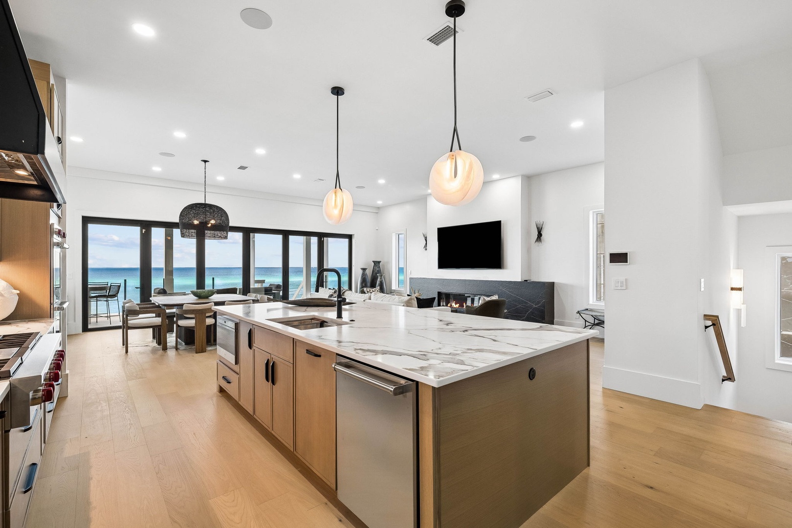 Step into your bright, open kitchen where ocean views greet you through floor-to-ceiling windows. The spacious island invites you to gather, cook, and share moments while the sea sparkles just beyond your terrace.