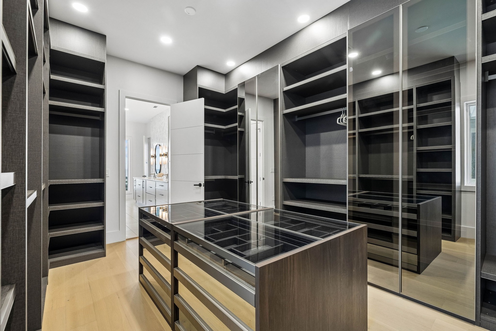 Step into your spacious walk-in closet with custom shelving, glass-front storage, and a center island—designed to keep your wardrobe beautifully organized and easily accessible.