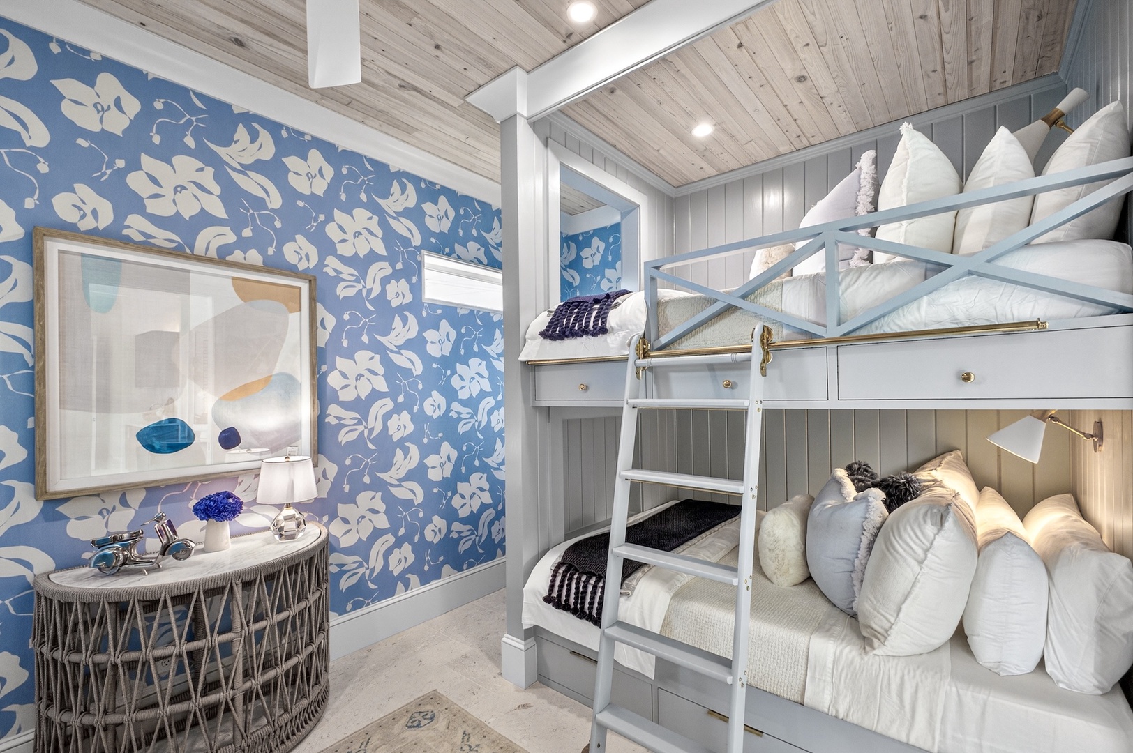Your coastal-chic bedroom features cozy bunk beds with plush pillows, inviting floral wallpaper, and charming nautical accents—perfect for peaceful seaside dreams.