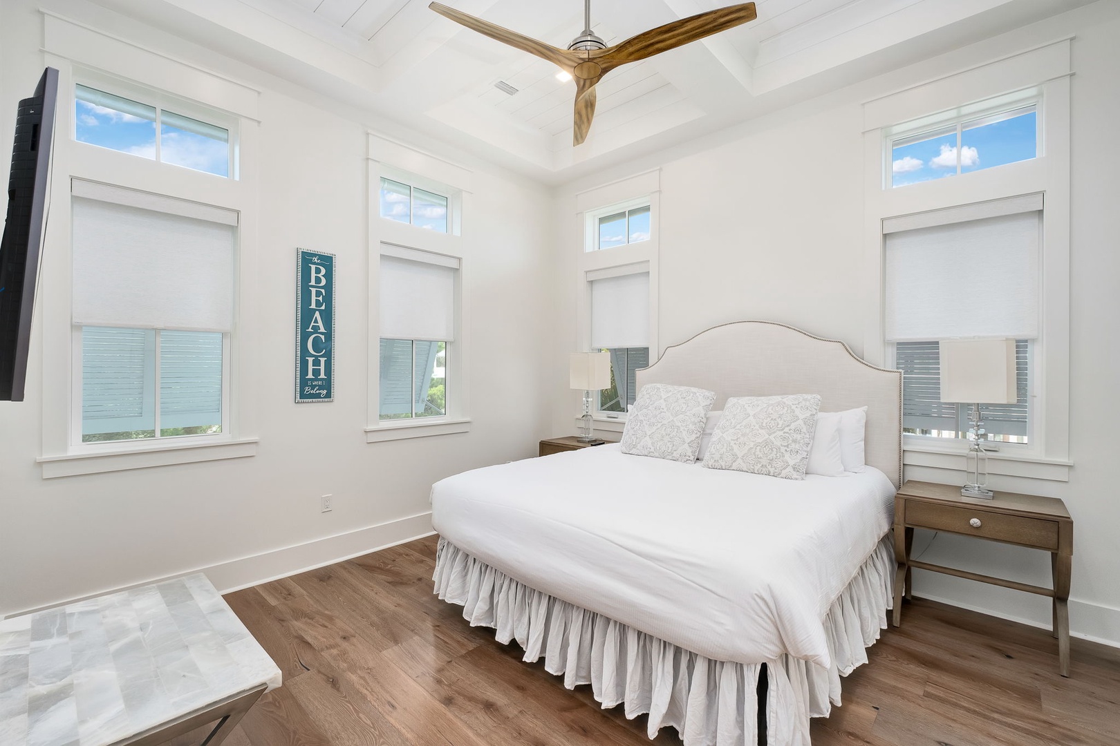 Your serene coastal bedroom features calming whites and coastal decor, with a glimpse of the beach through multiple windows to help you unwind in style.