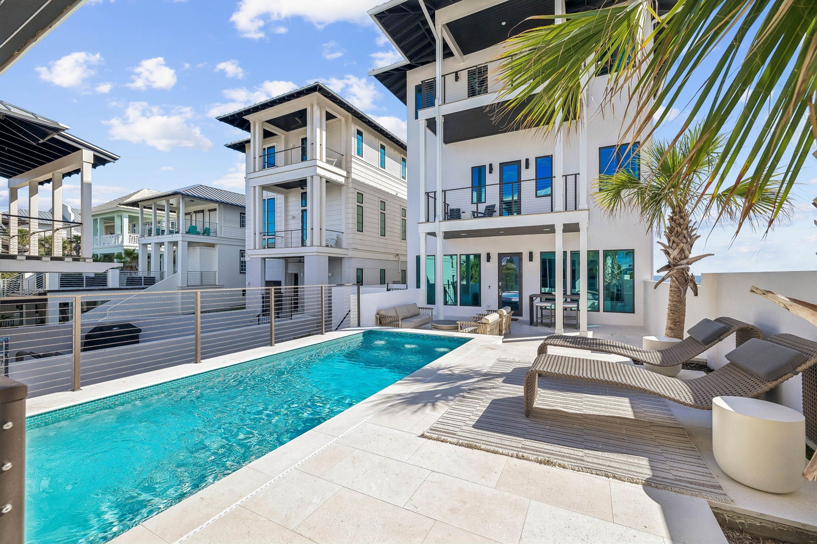 Step outside to your private pool deck where sun-soaked loungers await beneath swaying palms. The sparkling water invites you to cool off while you soak in bright blue skies and modern beachside living.