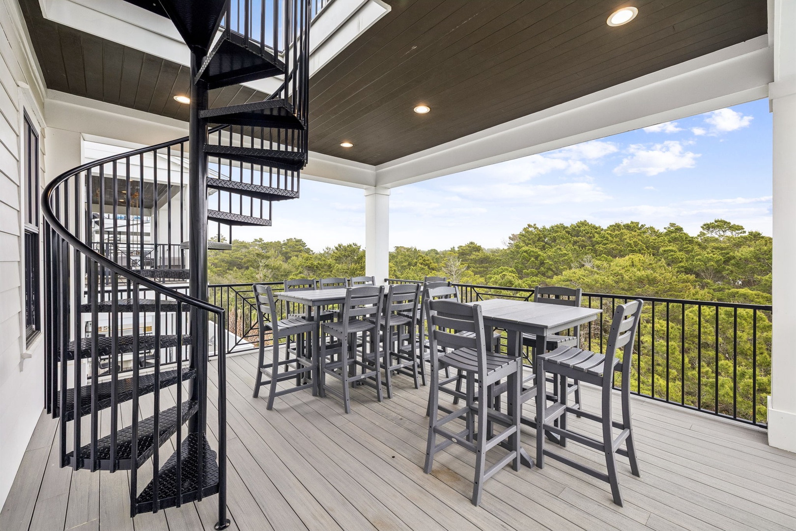 Sip your morning coffee on this elegant covered deck with panoramic treetop views and convenient spiral staircase access.
