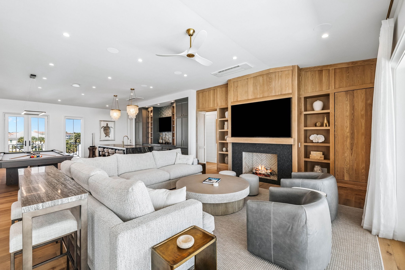 Step into your spacious living room where coastal elegance meets comfort. Sink into plush seating by the fireplace, enjoy game nights at the billiard table, and take in beautiful water views through oversized windows.
