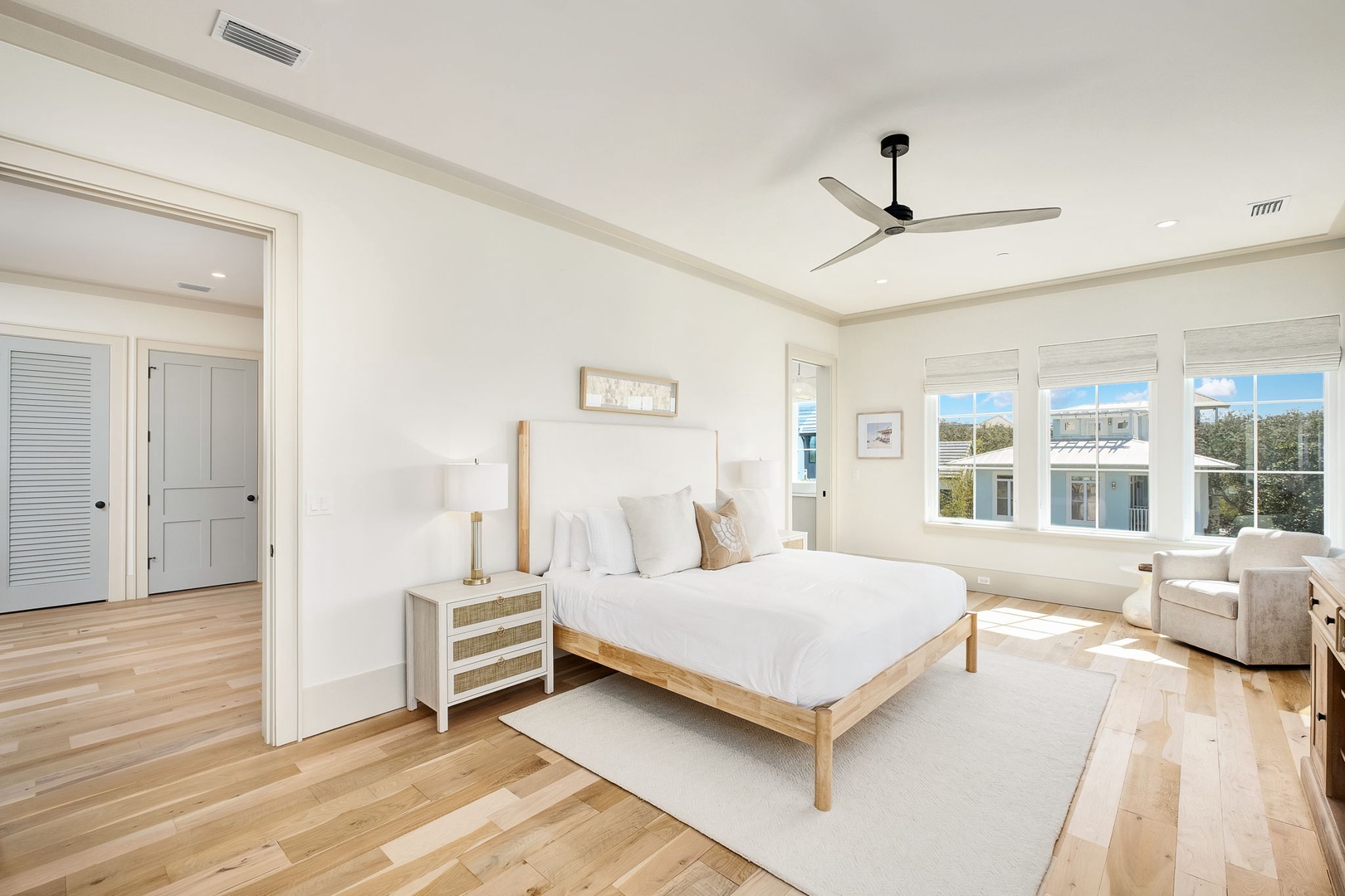 Drift off in this serene bedroom where coastal light floods through expansive windows and warm wood floors invite barefoot mornings.