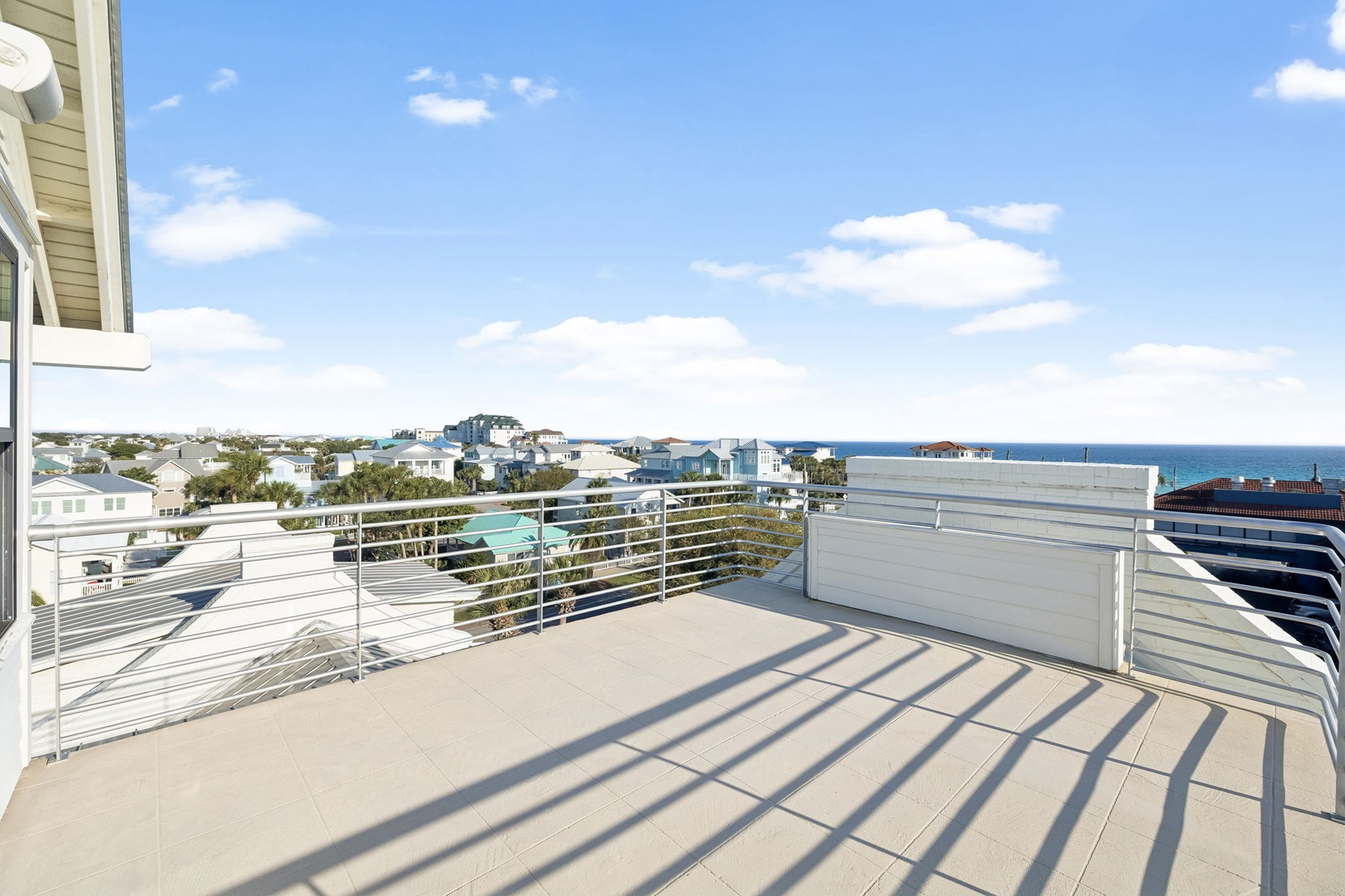 Spacious balcony with modern railings overlooking a charming coastal neighborhood and sparkling ocean views.