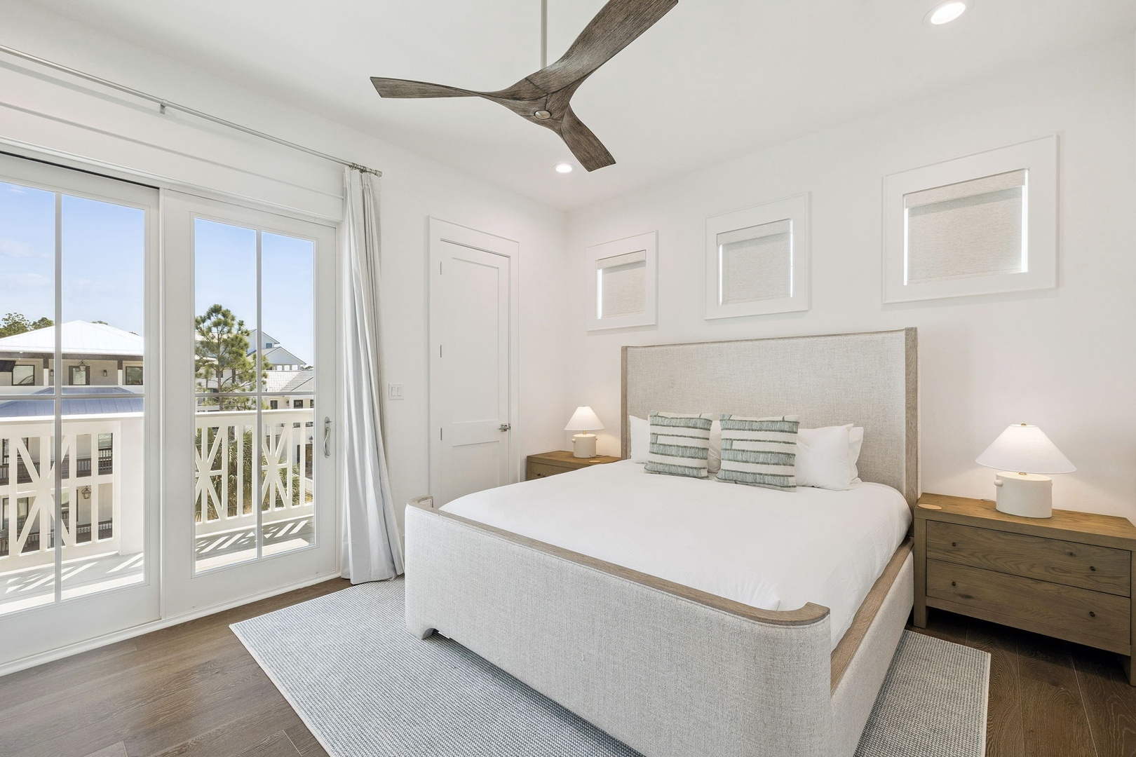 Drift off in your serene coastal bedroom with crisp linens, gentle ceiling fan breezes, and natural light streaming through French doors.