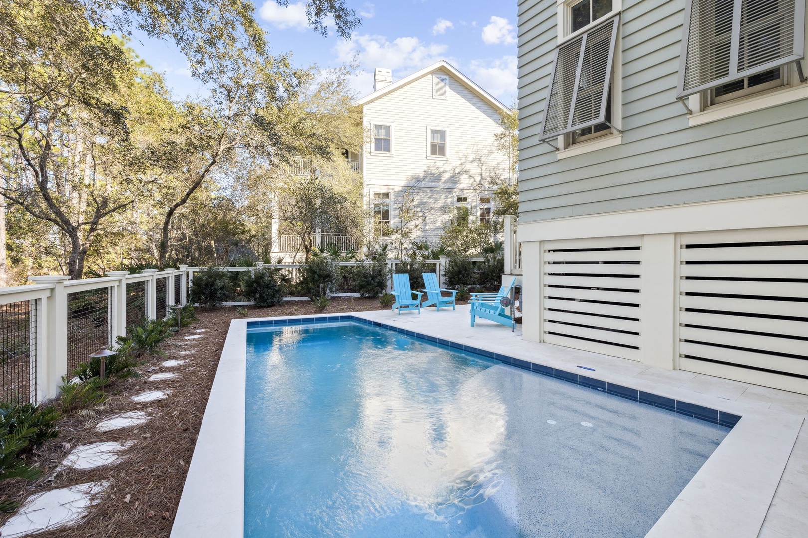 Dive into your private oasis with crystal-clear waters reflecting the sky, surrounded by cheerful blue chairs perfect for poolside relaxation.