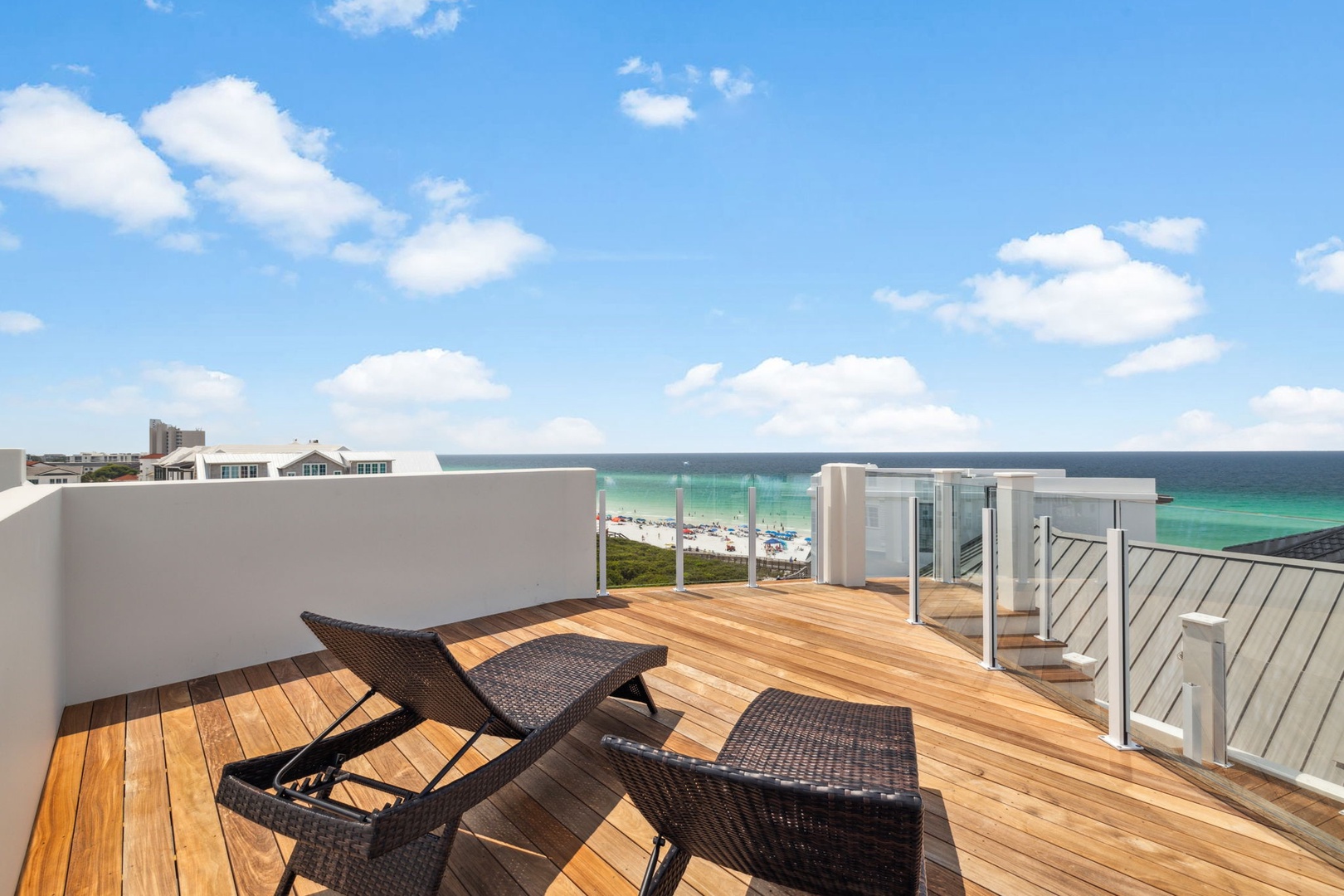 Stretch out on your private rooftop terrace and soak in endless ocean views. The warm wooden deck and loungers invite you to relax under bright skies, with the beach just steps away.