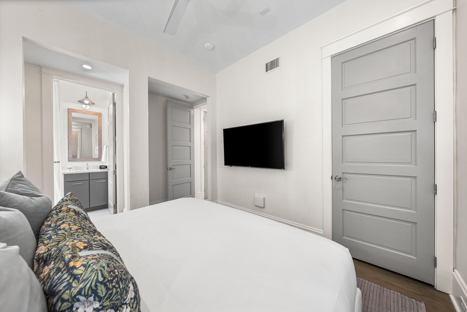 Rest in your elegant bedroom featuring crisp white linens, modern TV, and sleek en-suite bathroom access.
