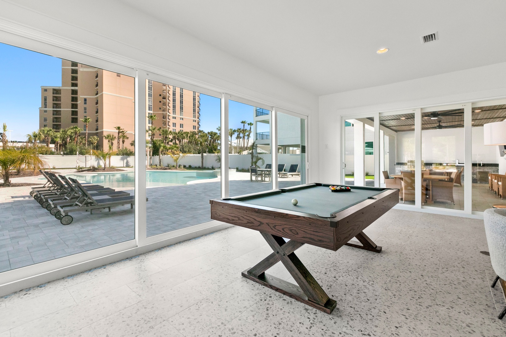 Challenge your companions to a friendly billiards match in this sun-drenched game room, where floor-to-ceiling windows frame palm trees and the sparkling pool just steps away.