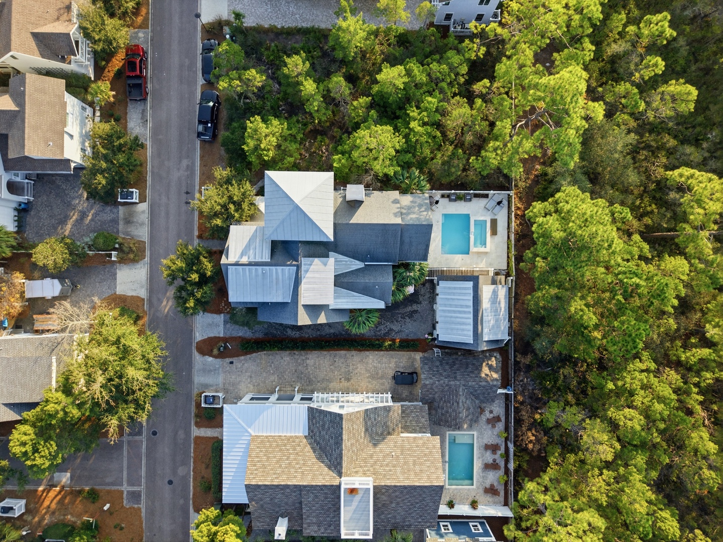 Aerial view captures the property nestled in a lush, tree-lined neighborhood, featuring a private pool and spacious grounds perfect for a secluded retreat.
