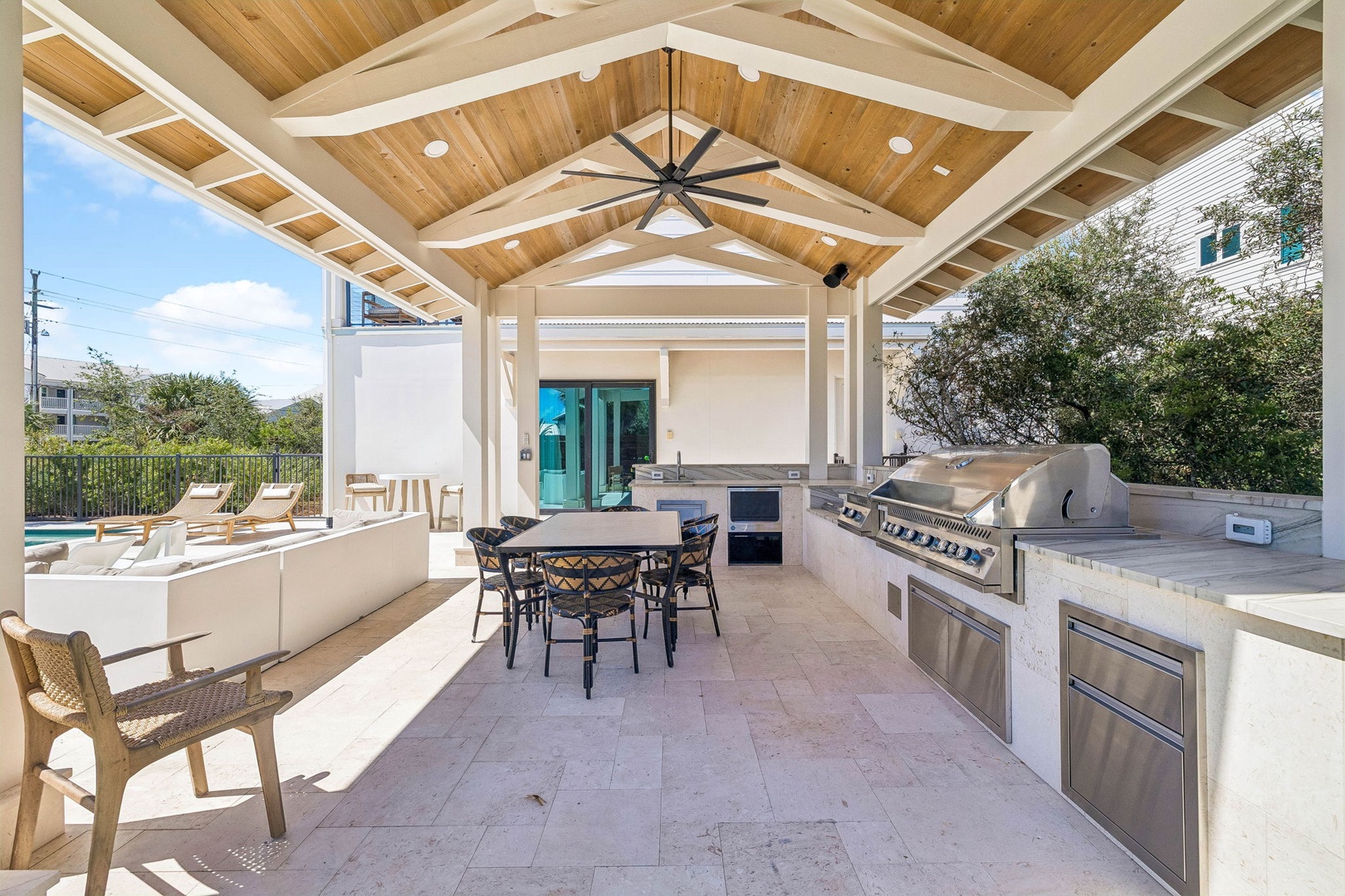 Your private outdoor kitchen awaits, complete with a full grill and dining space under soaring wood-beamed ceilings, just steps from the pool.