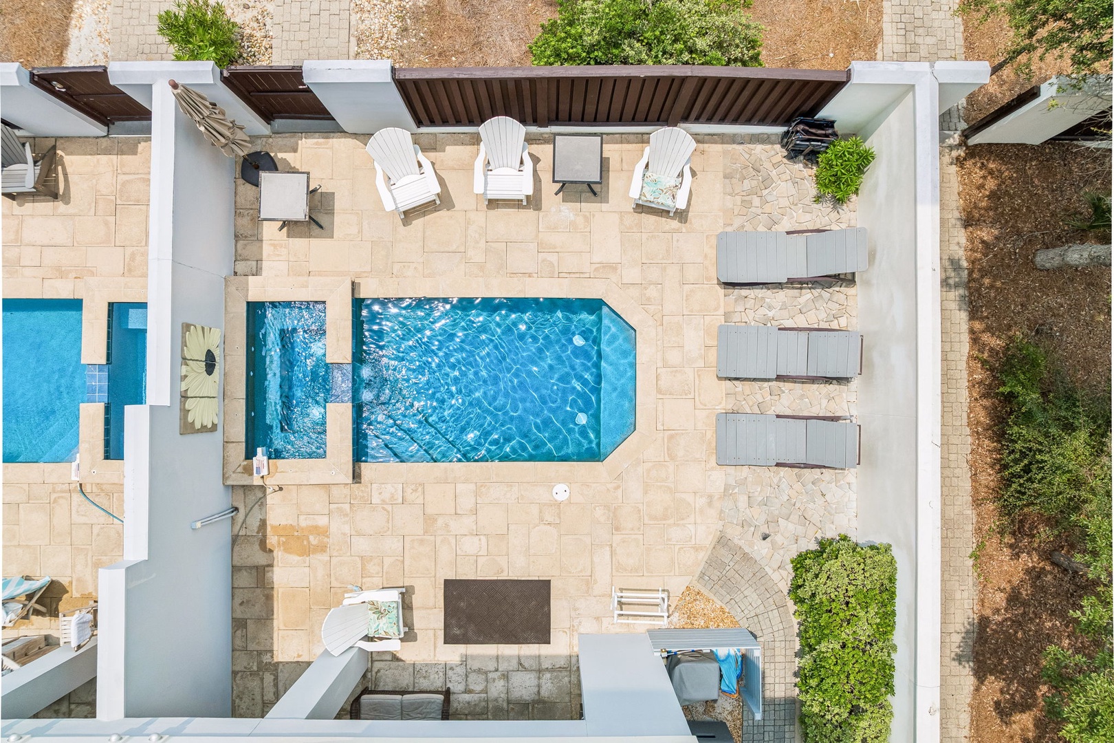 An aerial view of the property showcasing the private pool, sunbeds, and outdoor patio area surrounded by natural landscape.
