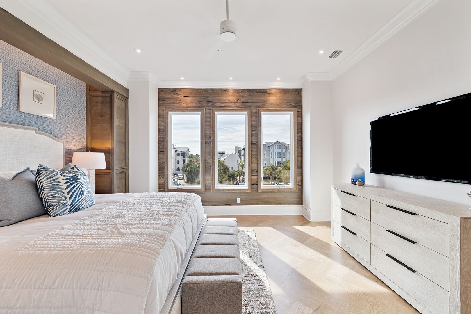 Sink into your plush bed and enjoy views of coastal charm through rustic wood-framed windows, with a flat-screen TV and crisp, modern style for ultimate relaxation.