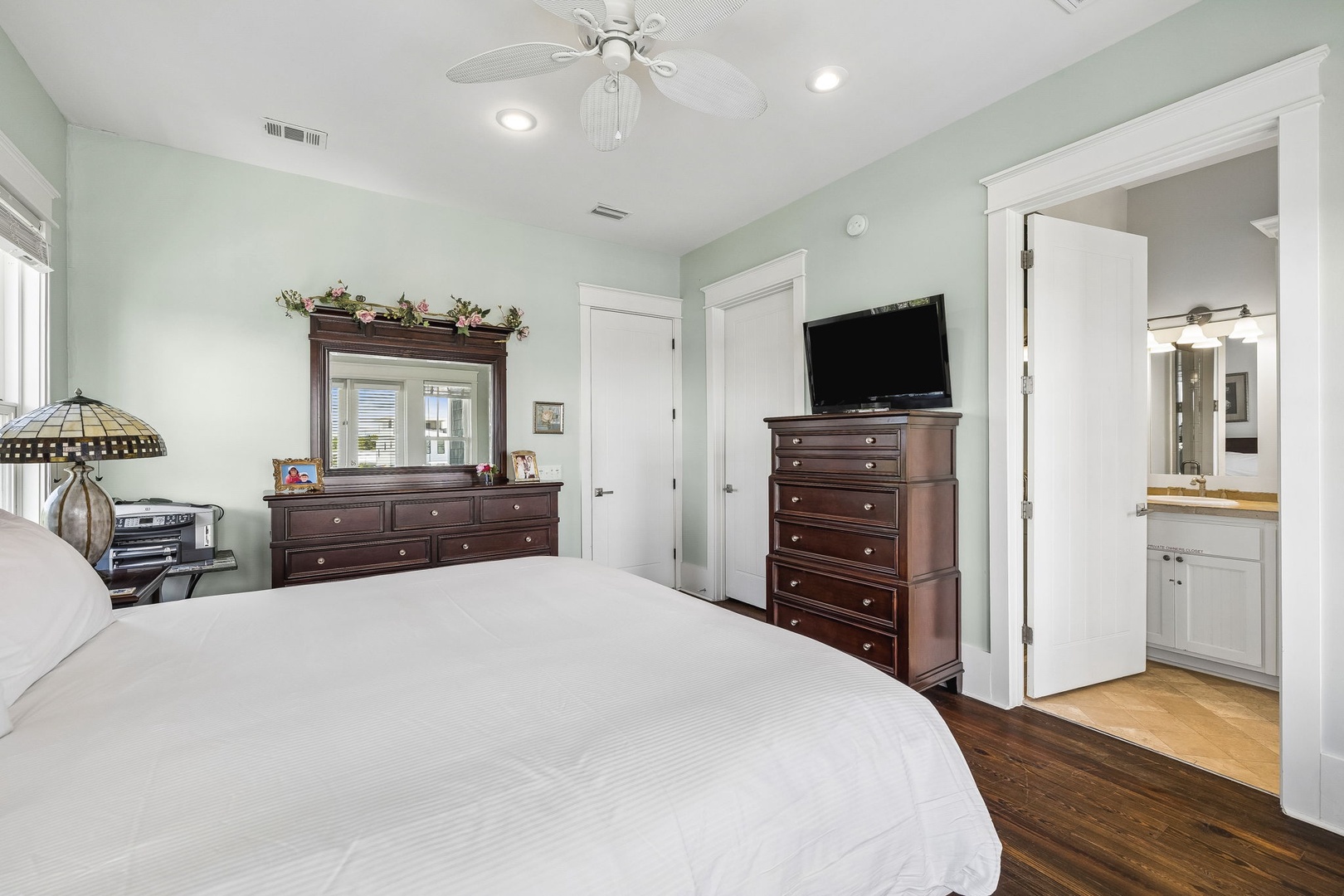 Unwind in your serene bedroom sanctuary with calming coastal tones, elegant wood furnishings, and your own private ensuite. The ceiling fan keeps you comfortable while you relax in this tranquil space.