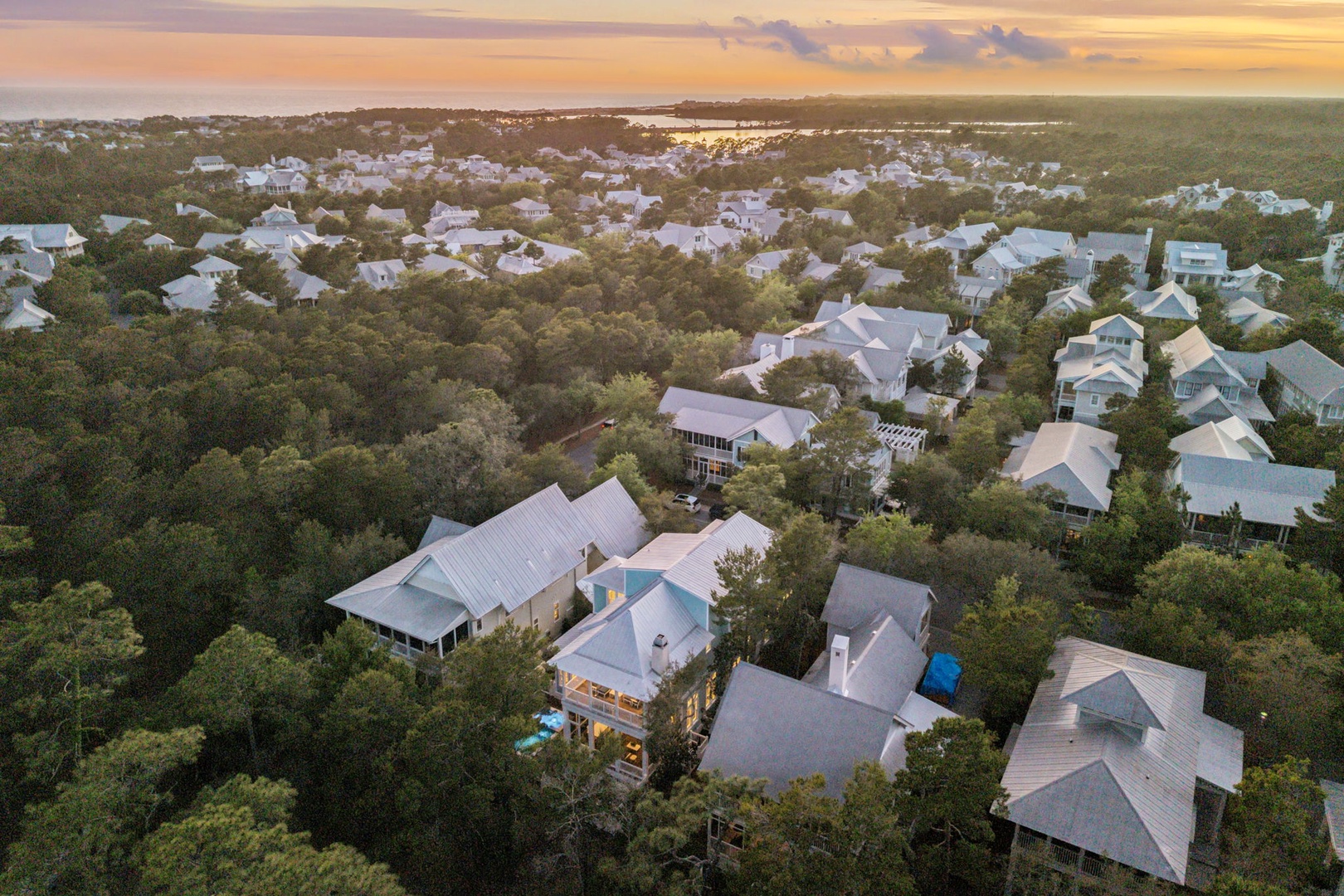 Aerial view of coastal community with homes nestled among lush trees, offering peaceful waterfront neighborhood charm near the shoreline.