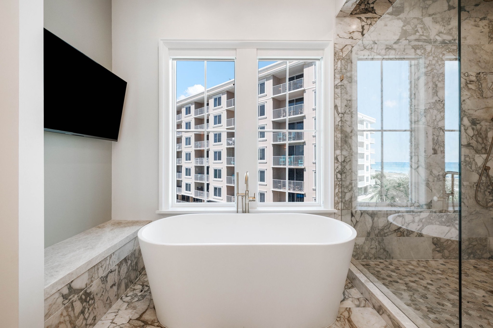 Slip into your own private retreat—a sleek soaking tub centered in marble elegance, with sunshine and ocean breezes just beyond your window.