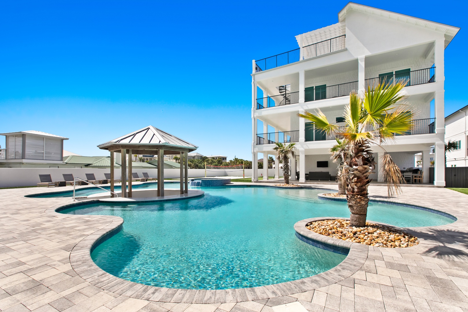 Stunning modern beachside property featuring an expansive custom pool, tropical palms, and spacious balconies overlooking the resort-style grounds, perfect for your unforgettable coastal escape.