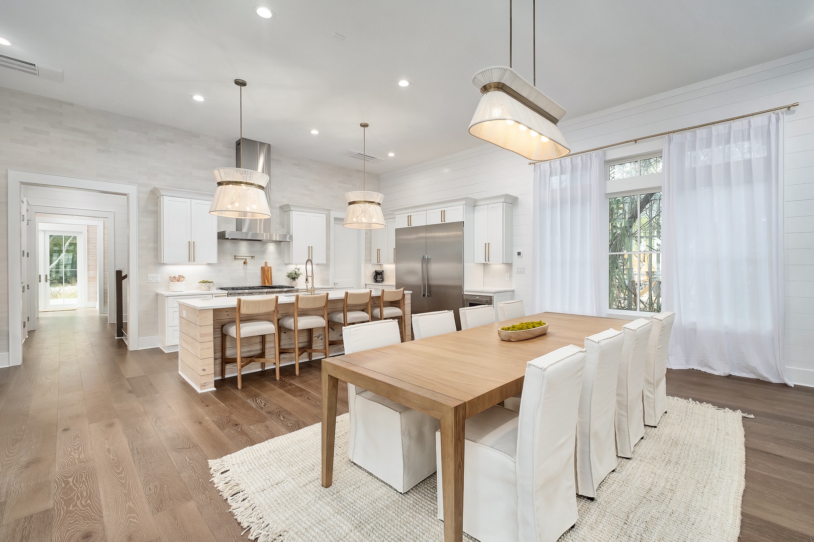 You'll love cooking and dining in this stunning open-plan space featuring crisp white cabinetry, warm wood accents, and elegant pendant lighting.