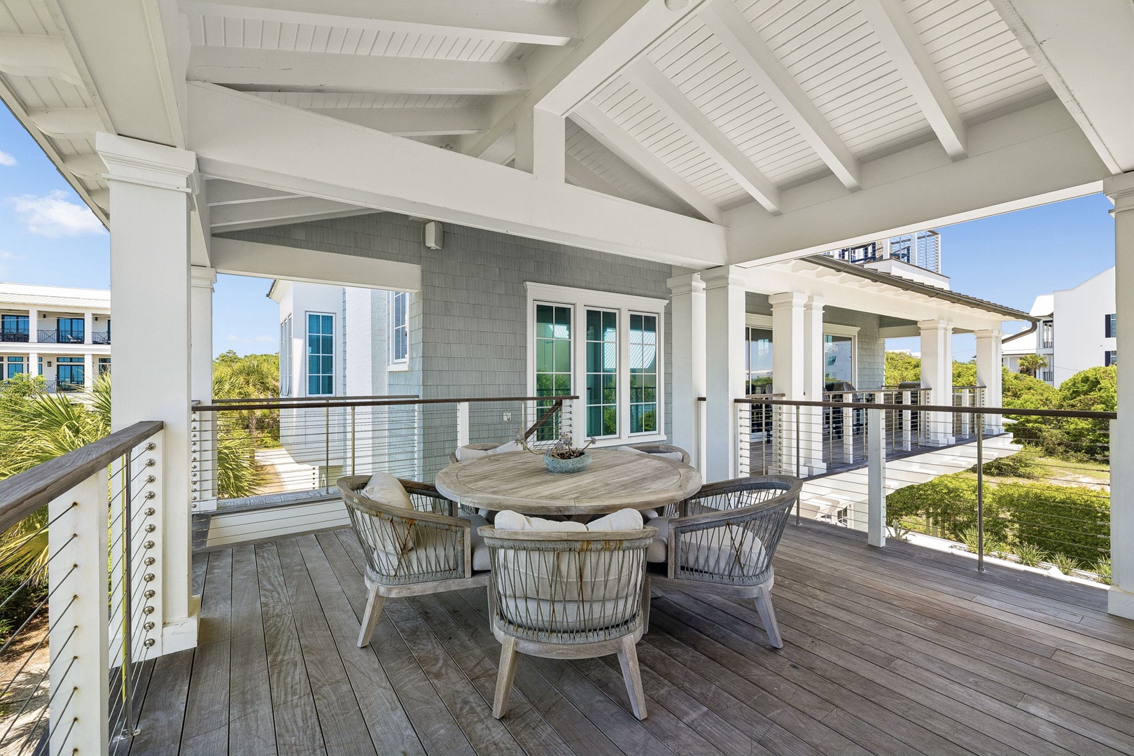 Picture yourself dining outdoors under soaring vaulted ceilings—this covered balcony blends shade and sunshine, inviting coastal breezes and scenic glimpses of lush greenery all around you.
