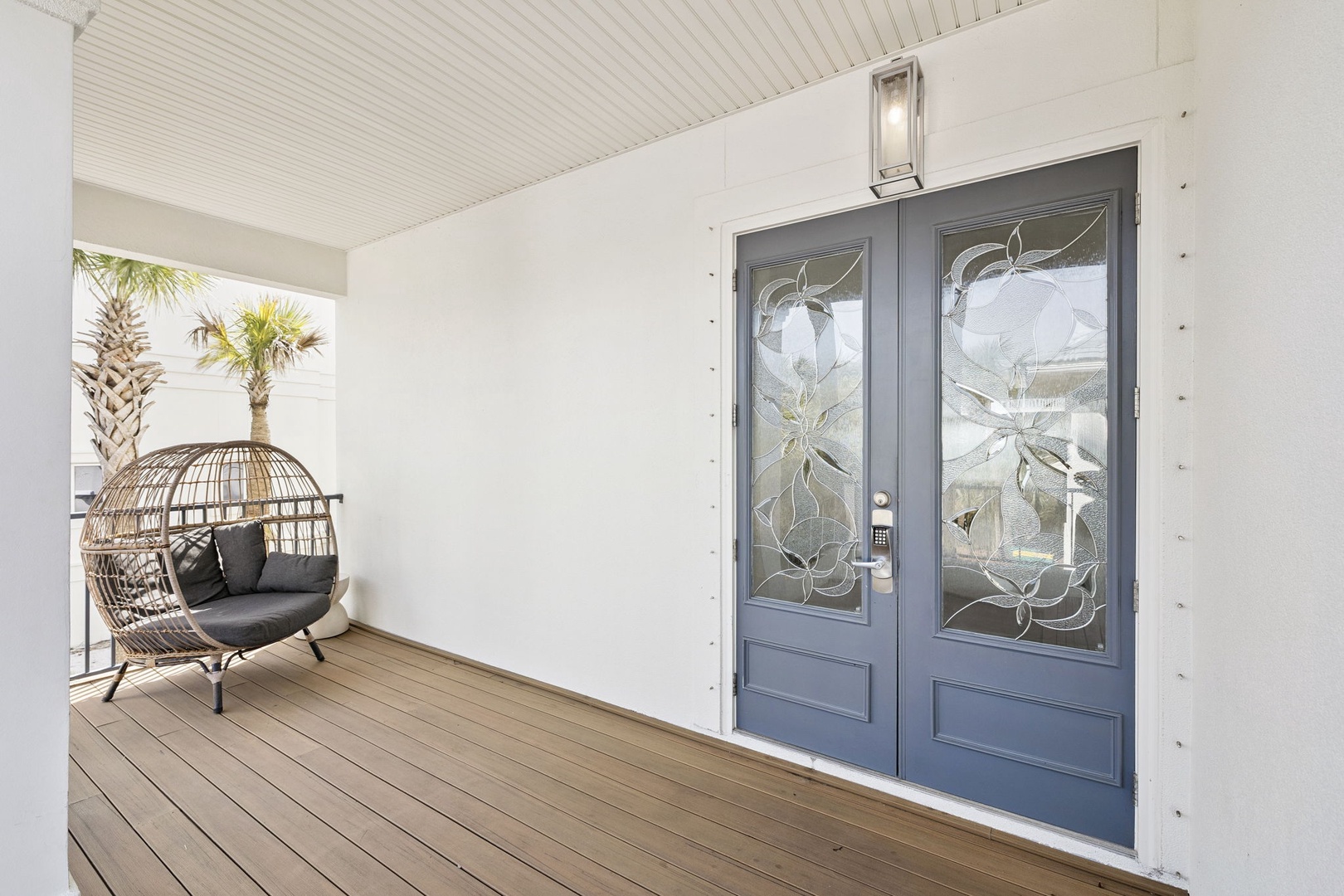Stylish entrance with decorative glass doors and tropical palms creating a welcoming arrival experience.