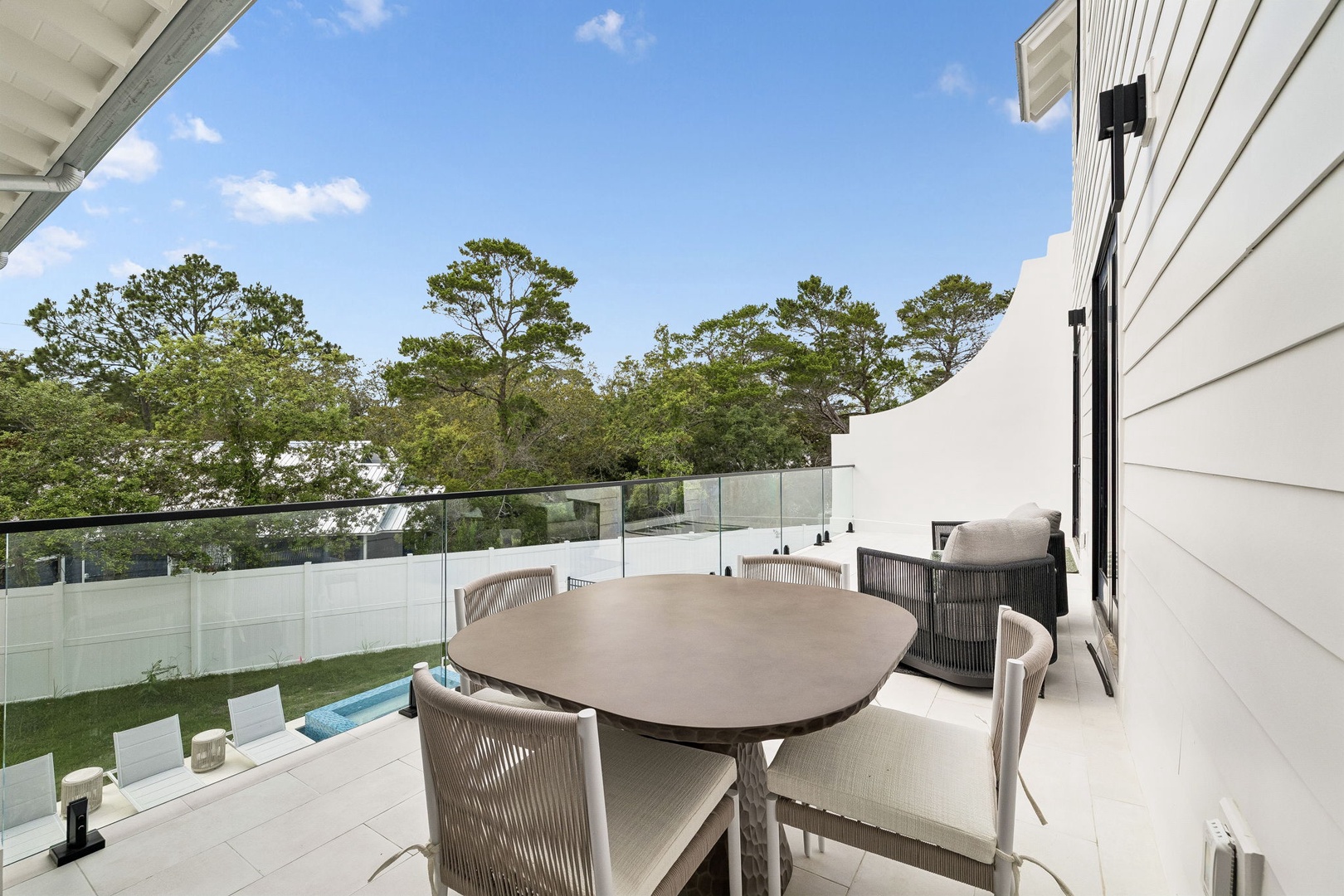 Stylish second-floor terrace with dining for four overlooking lush trees and backyard pool—ideal for morning coffee or al fresco meals in the fresh air.