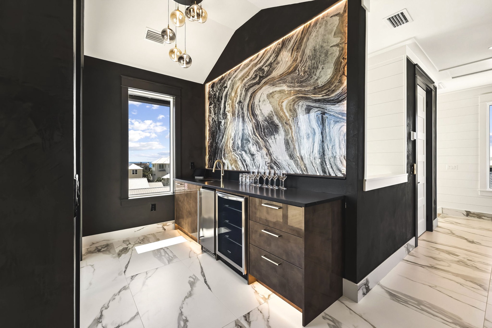 A wet bar with stunning marble countertops, sleek cabinetry, and your own beverage fridge for easy entertaining. Bold marble art and modern pendant lighting create a sophisticated space for gathering.