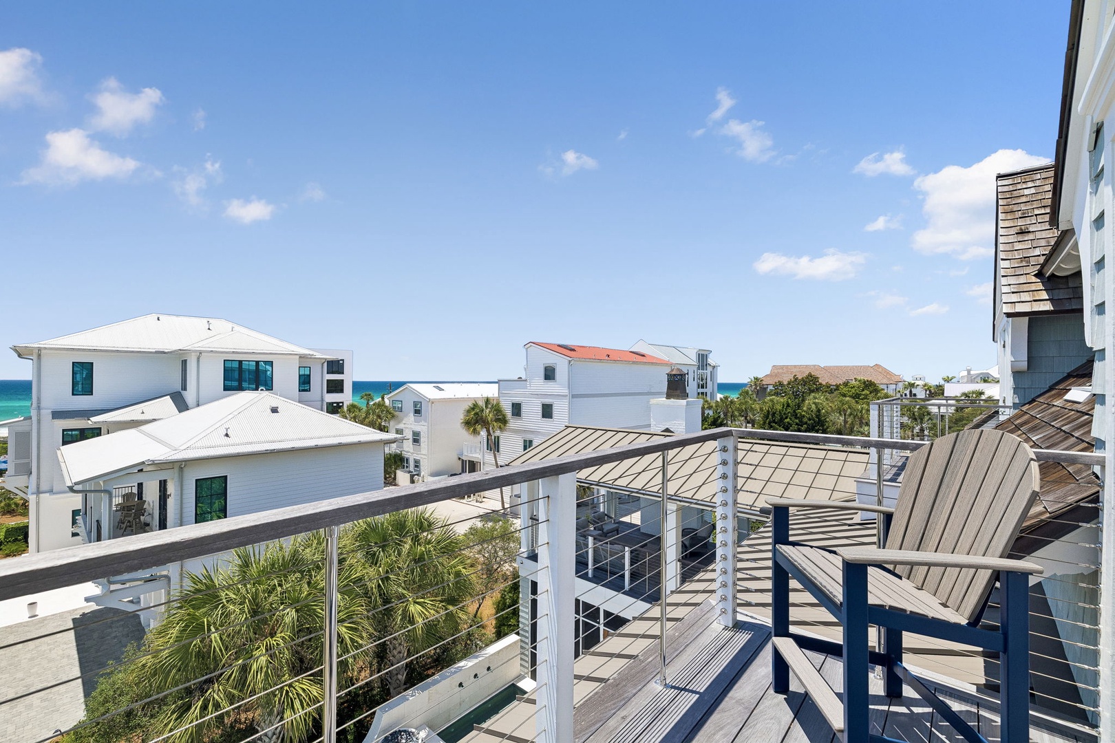 A rooftop deck overlooking coastal homes, offering partial sea views beneath a clear blue sky.