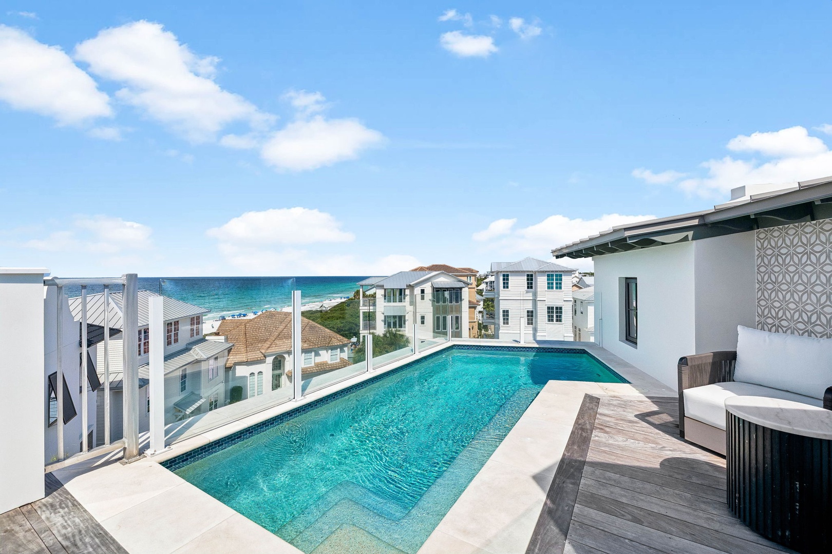 Stunning rooftop pool and terrace overlook turquoise Gulf waters, offering a private coastal retreat steps from the beach with modern lounge seating and sweeping ocean views.