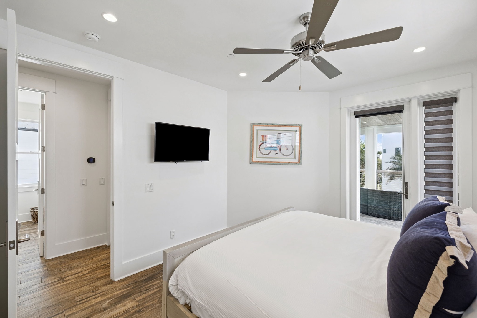 Unwind in your bright, airy bedroom with crisp linens, ceiling fan, and wall-mounted TV for cozy evenings after exploring.