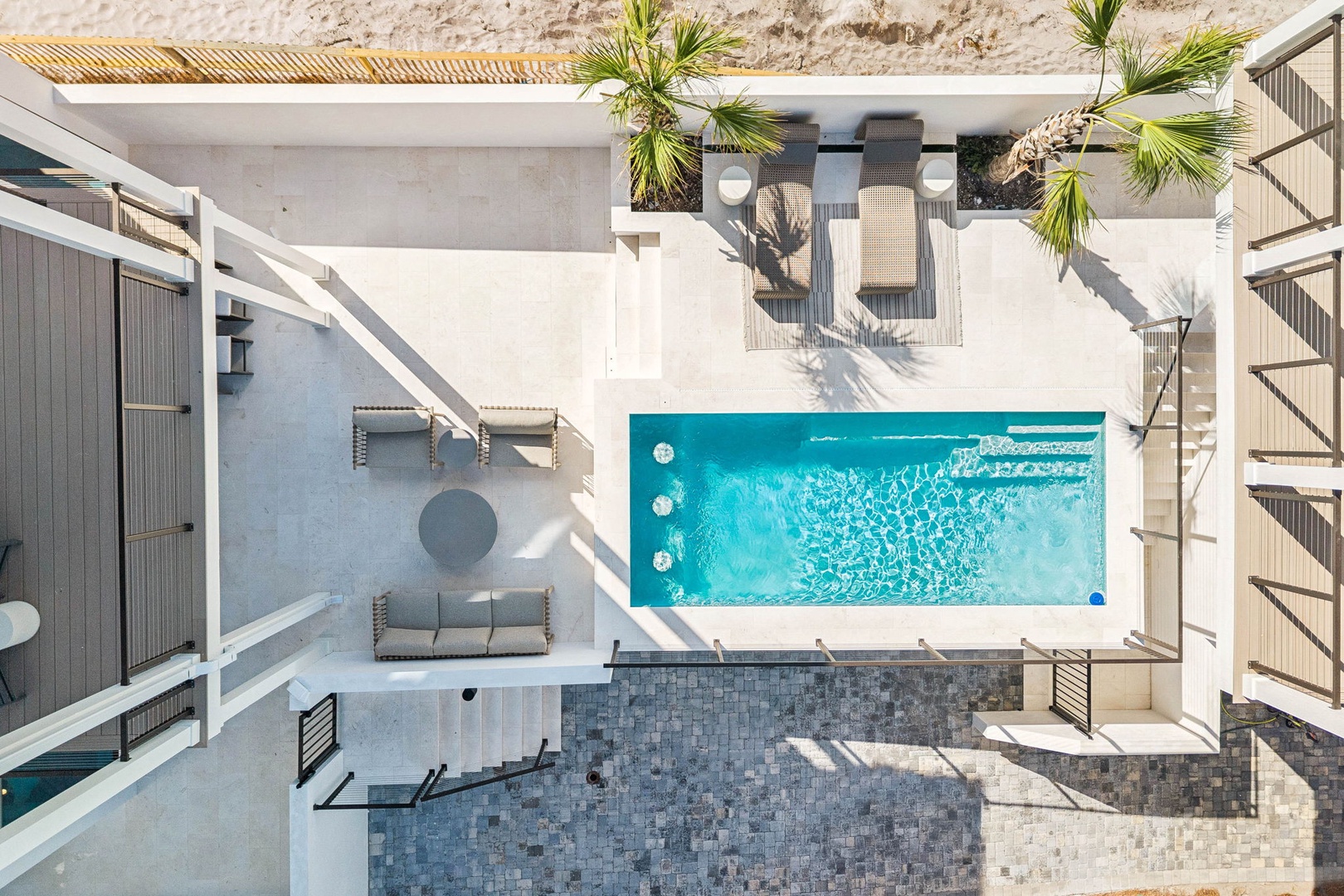 Stunning aerial perspective captures the property's outdoor layout with private pool surrounded by sun-drenched terraces, cozy lounging nooks, and tropical greenery framing your modern coastal retreat.