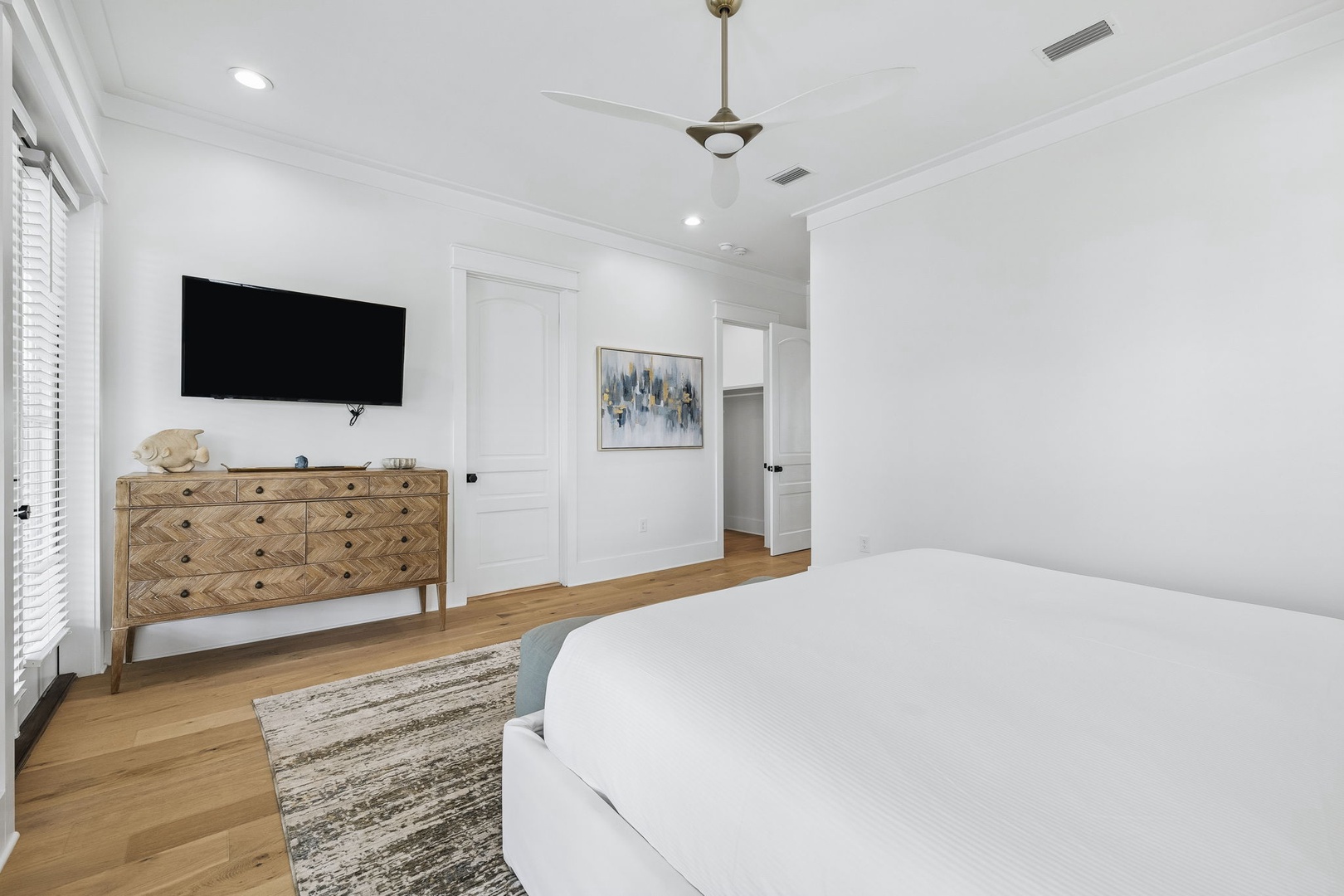 Your bright, serene bedroom awaits with crisp white linens, warm wood floors, and plenty of natural light streaming through the windows—a peaceful retreat after exploring.