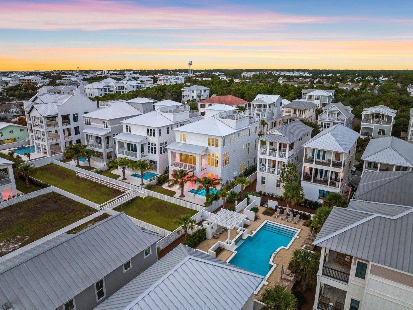 Beautiful coastal neighborhood with modern vacation homes featuring pools and landscaped grounds at golden hour.