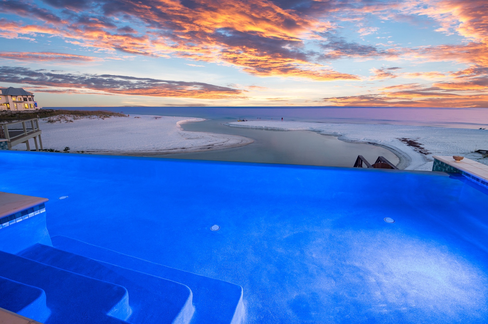 A beachfront property offering pool and ocean access, located in a coastal area with striking sunset views over the water.