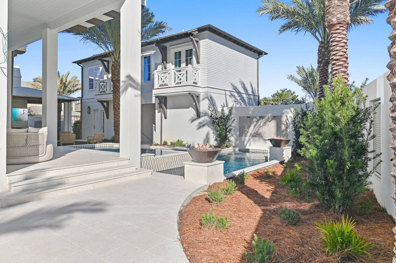 Step out to your private oasis where palms sway, the pool sparkles, and a shaded patio invites you to unwind in coastal elegance under sunny skies.