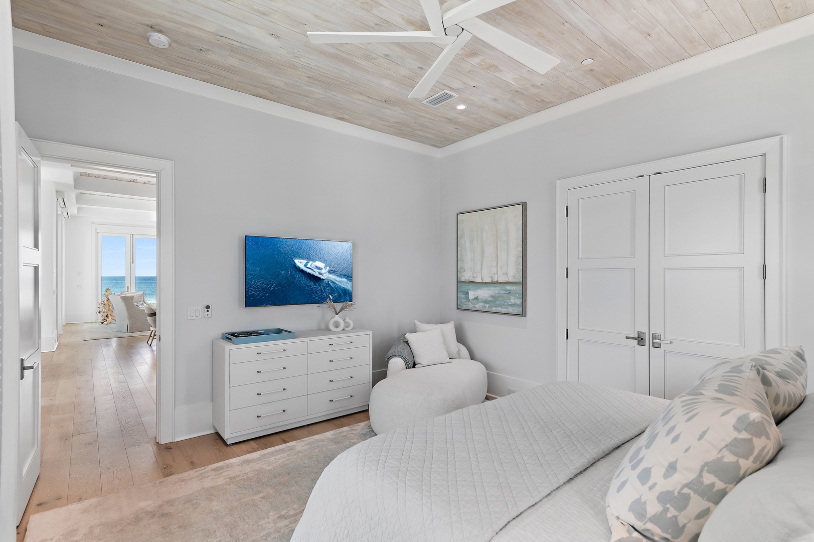 Your bedroom opens to a sun-soaked coastal retreat. Feel the ocean breeze through open doors revealing blue waters and white sand steps away. Relax in this serene, light-filled space designed for peaceful getaways.